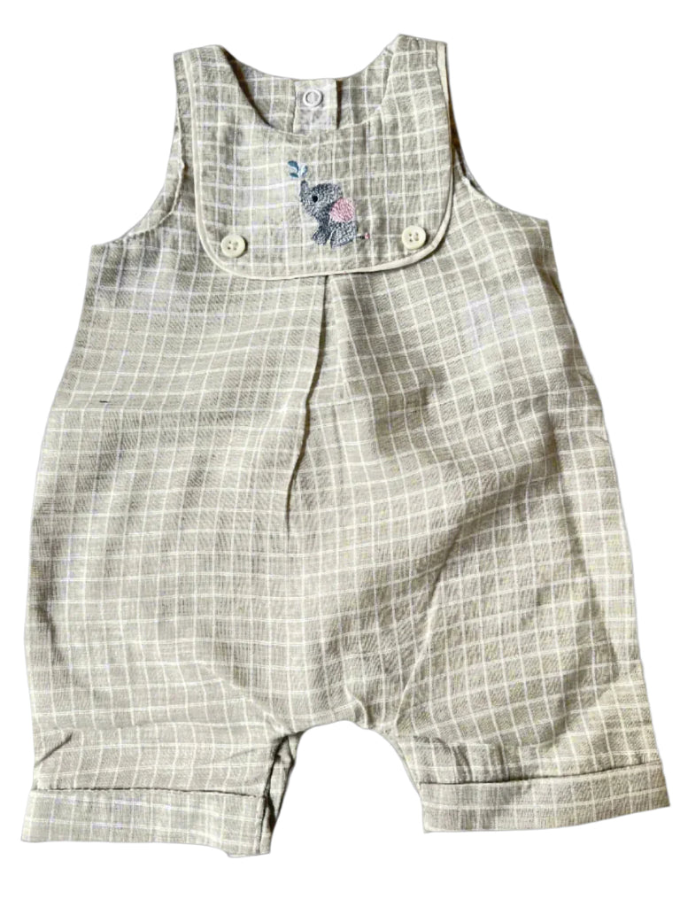 Plaid baby romper on a beige surface